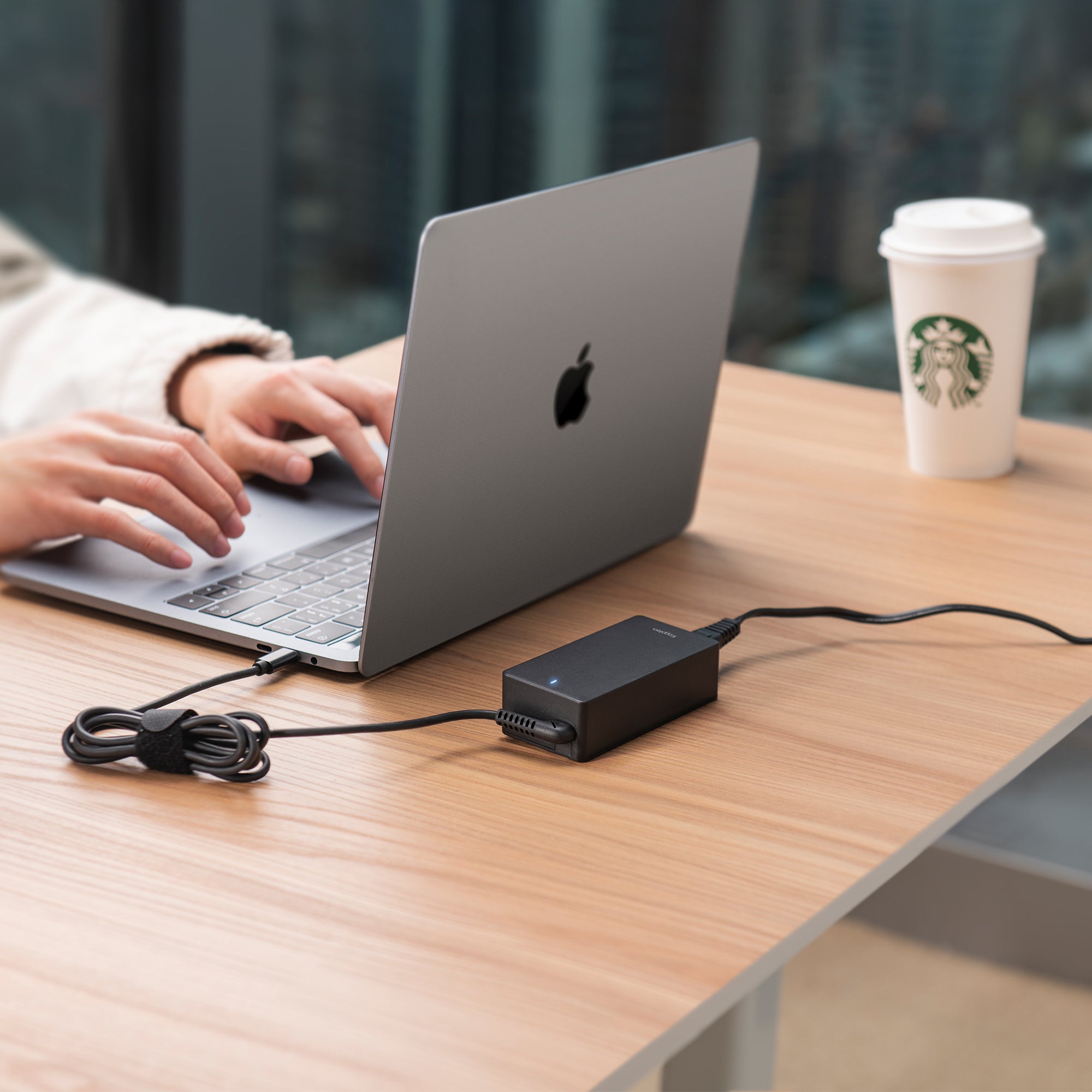 Power adapter plugged into macbook via USB-C cable on coffee table