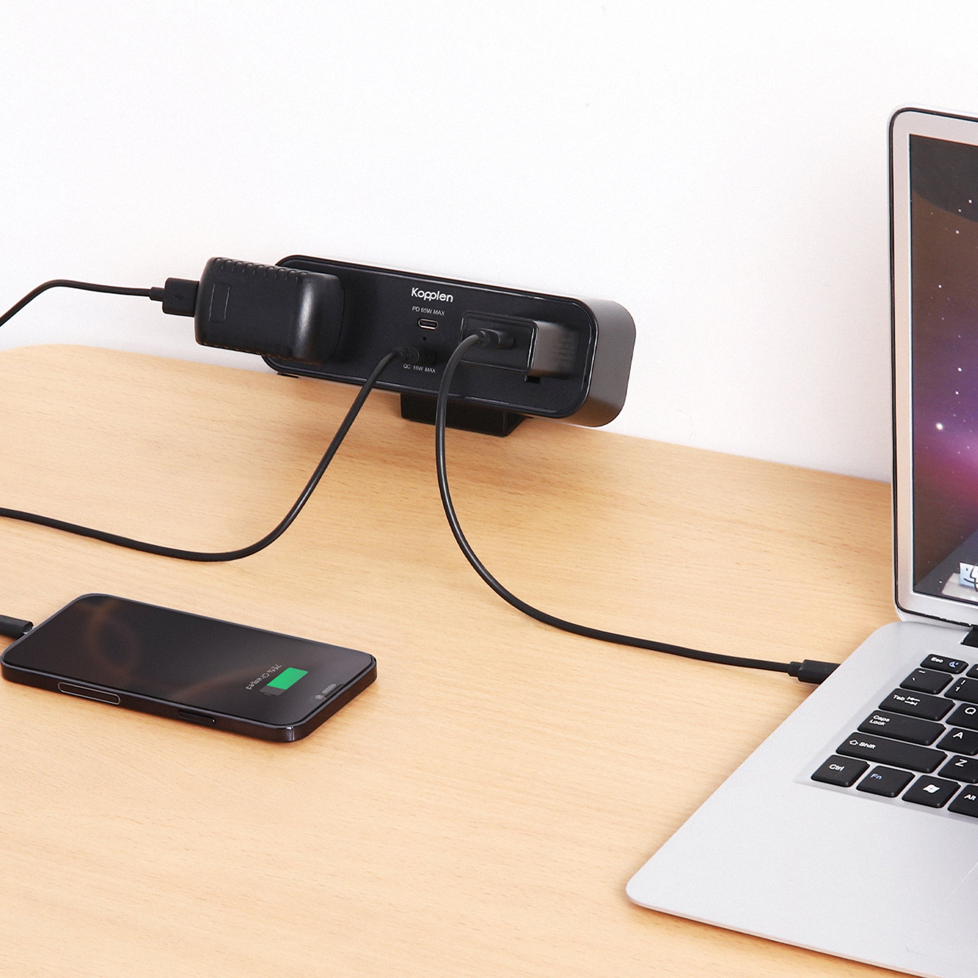 Power strip attached to desk with phone and computer plugged into it