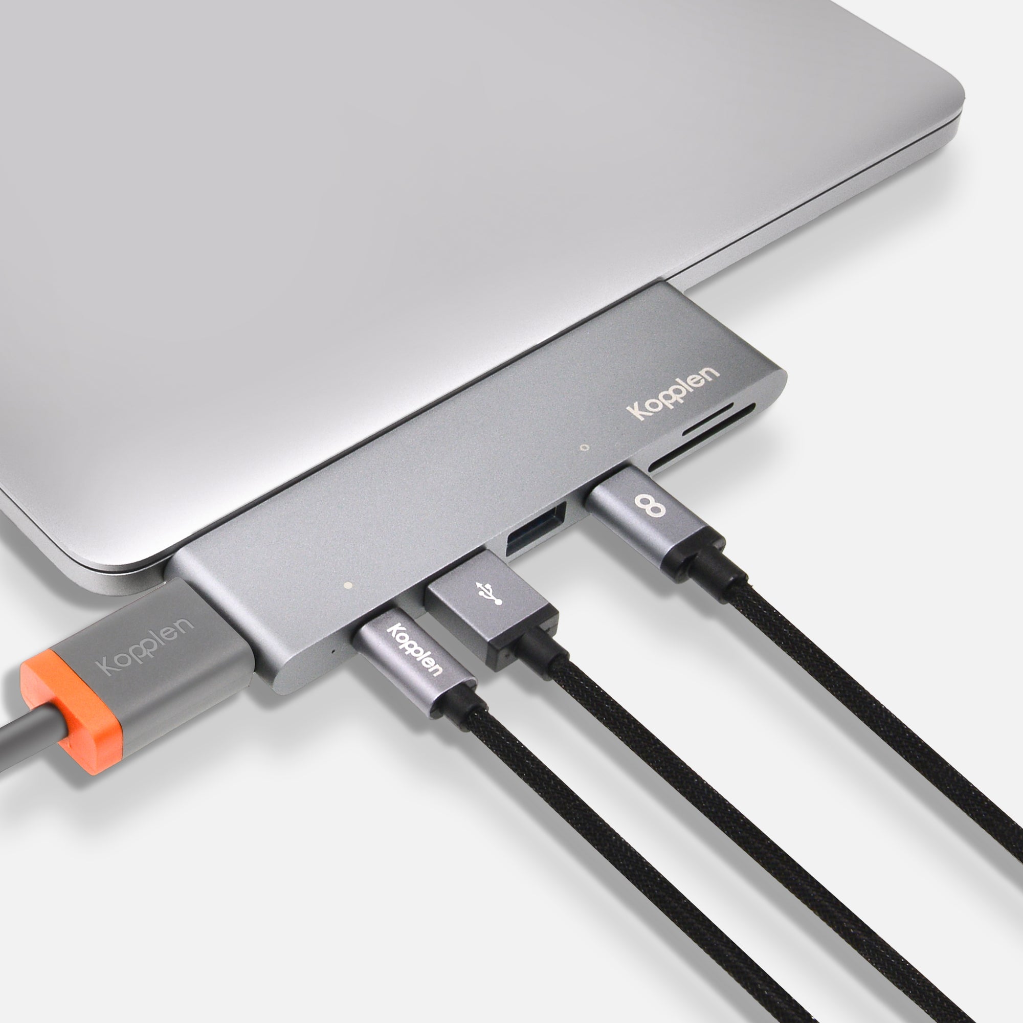 Hub plugged into MacBook with many cables plugged into the hub displaying its connectivity expansion