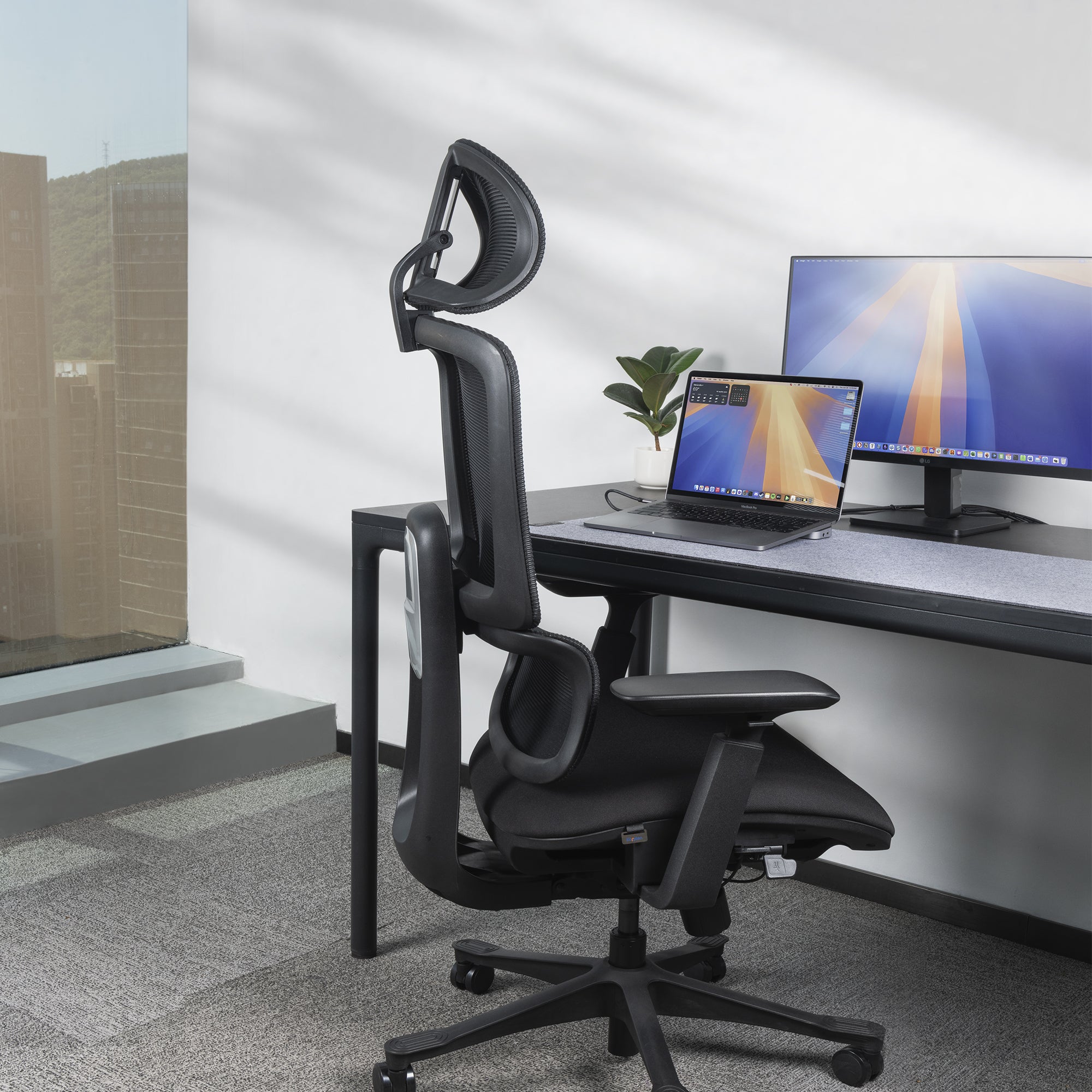 Side profile view of nucleus office chair at a desk with MacBook and monitor