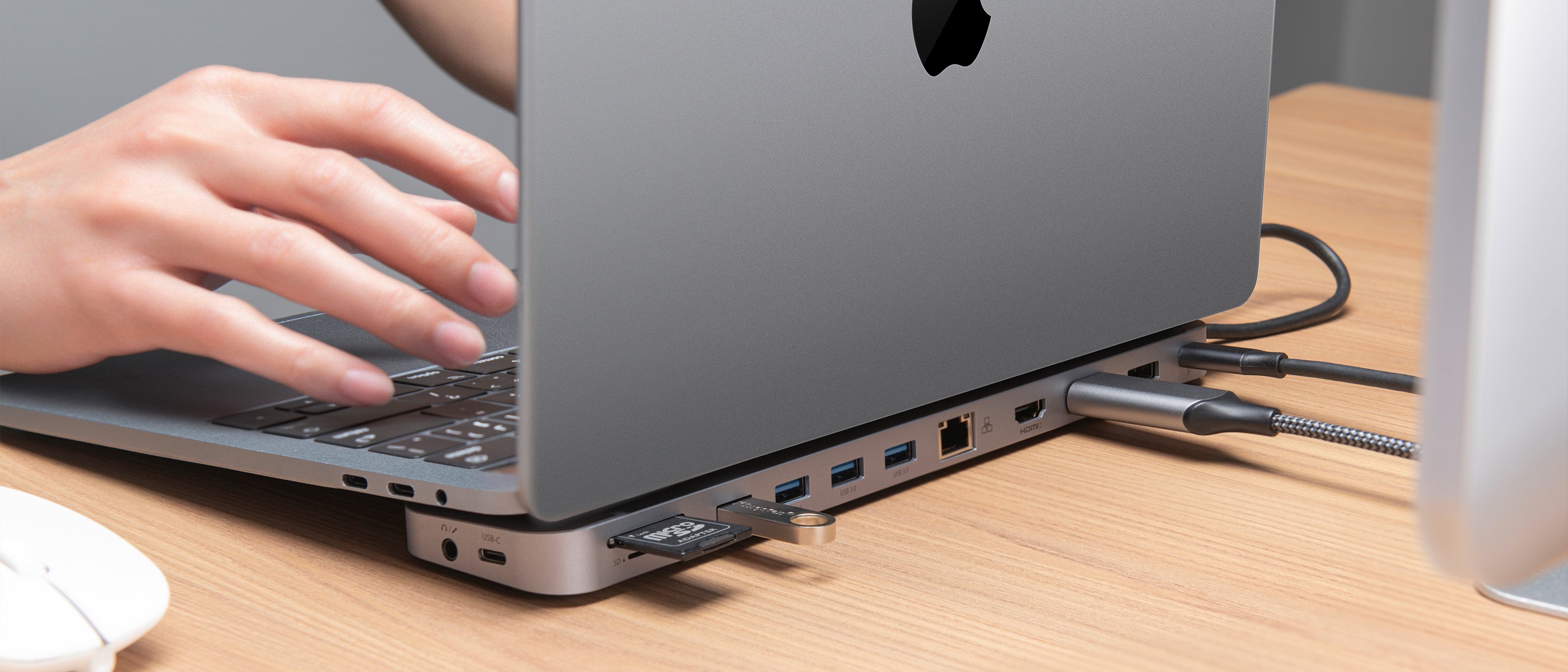 Macbook on docking station with various cables and memory devices plugged into it