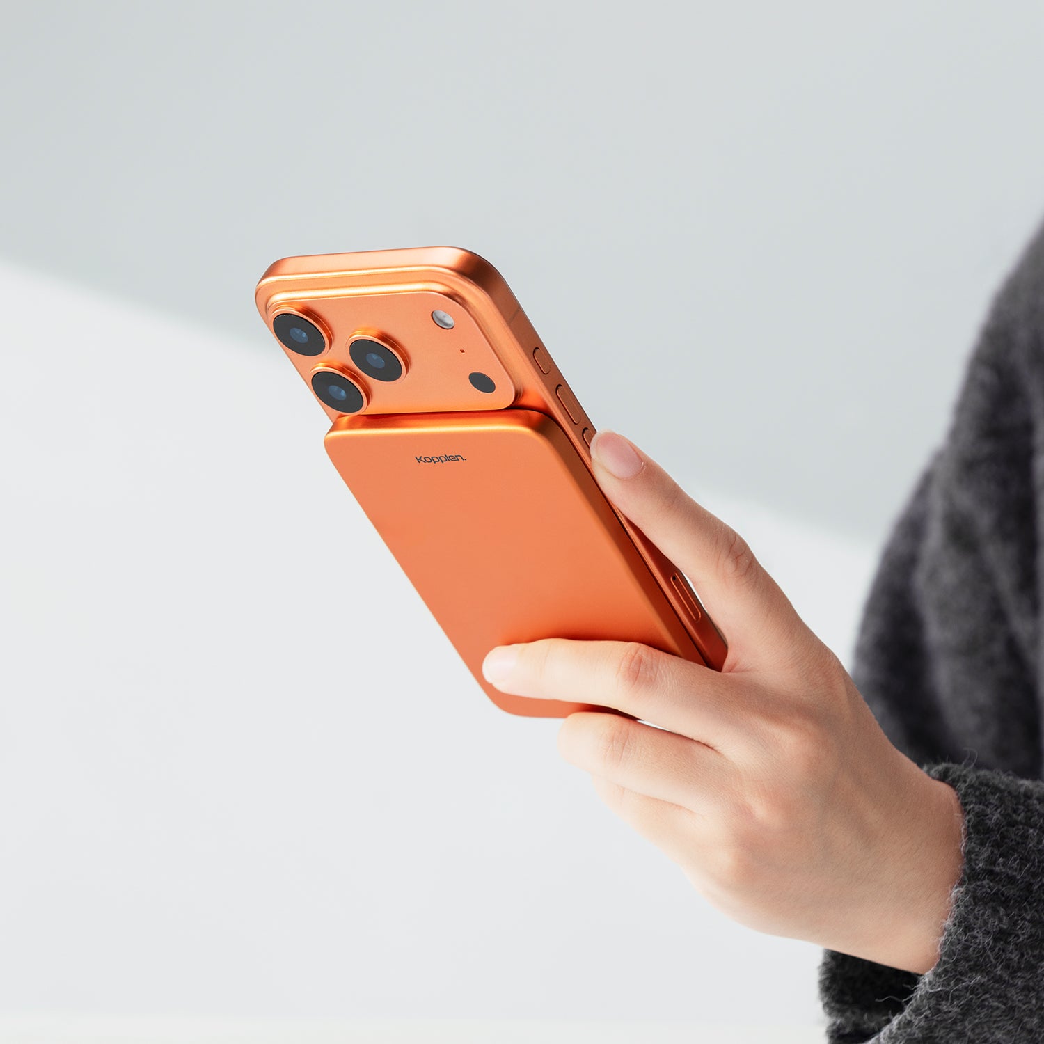 Person holding an orange smartphone with a plain background