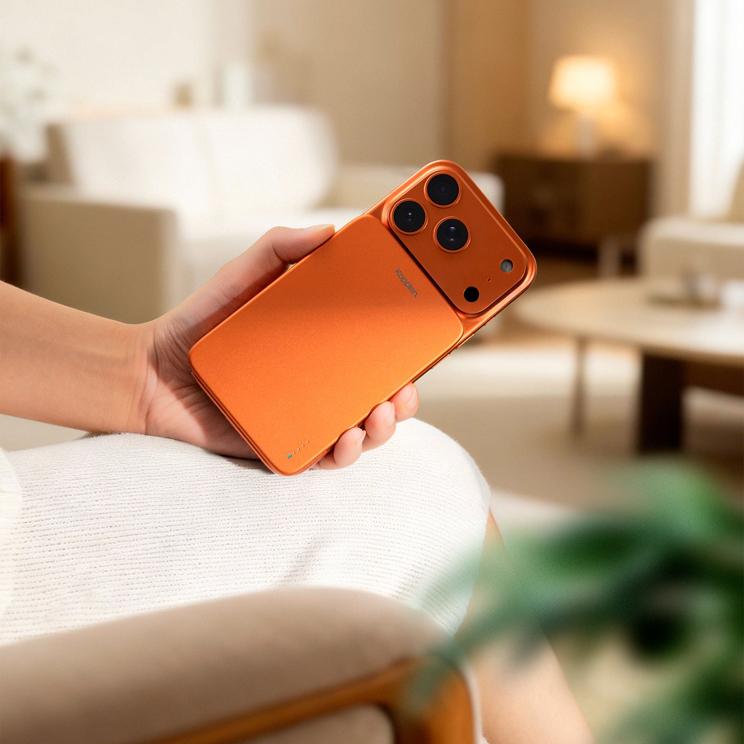 Person holding an orange smartphone in a blurred indoor setting
